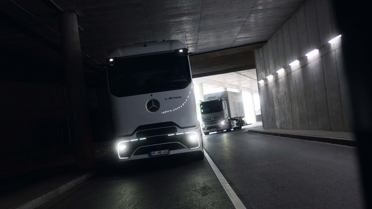 Dva eActros 400, jedan sa ProCabin i jedan sa proverenom kabinom, voze kroz mračan tunel sa upaljenim farovima. Na kraju tunela vidi se jarko dnevno svetlo, što stvara kontrast sa tamnim okruženjem.